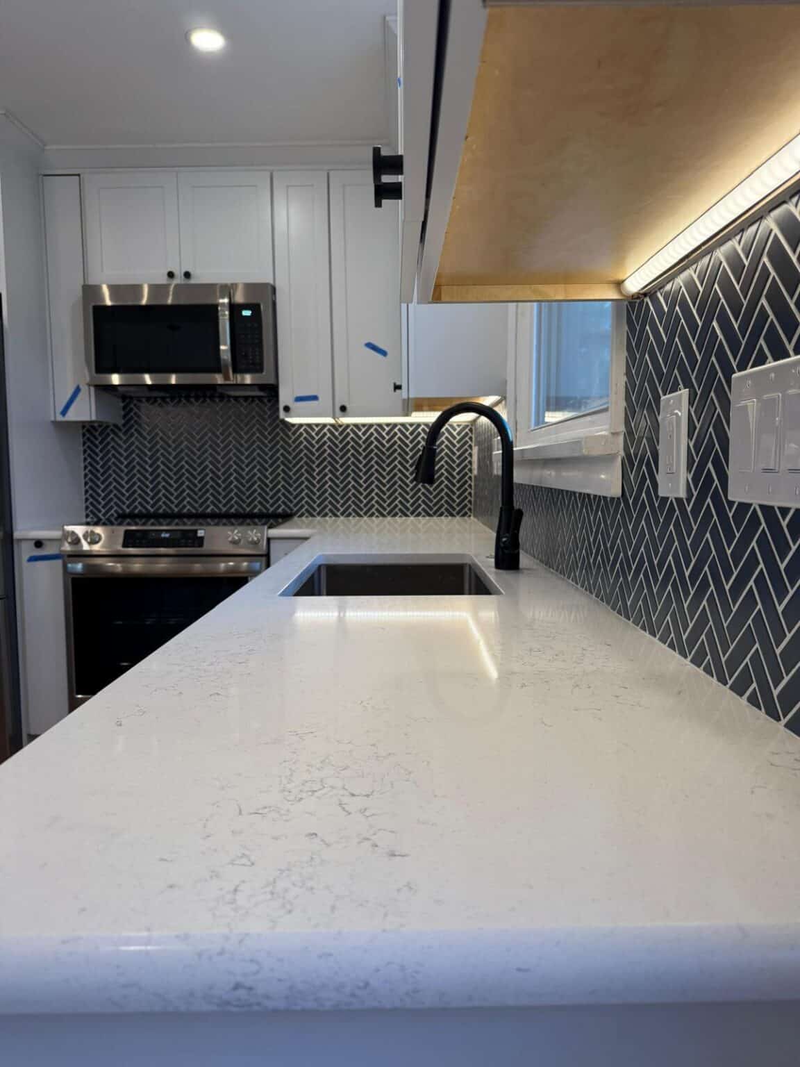 Kitchen with herringbone tile on the wall and marble countertop. Home Remodeling Contractor